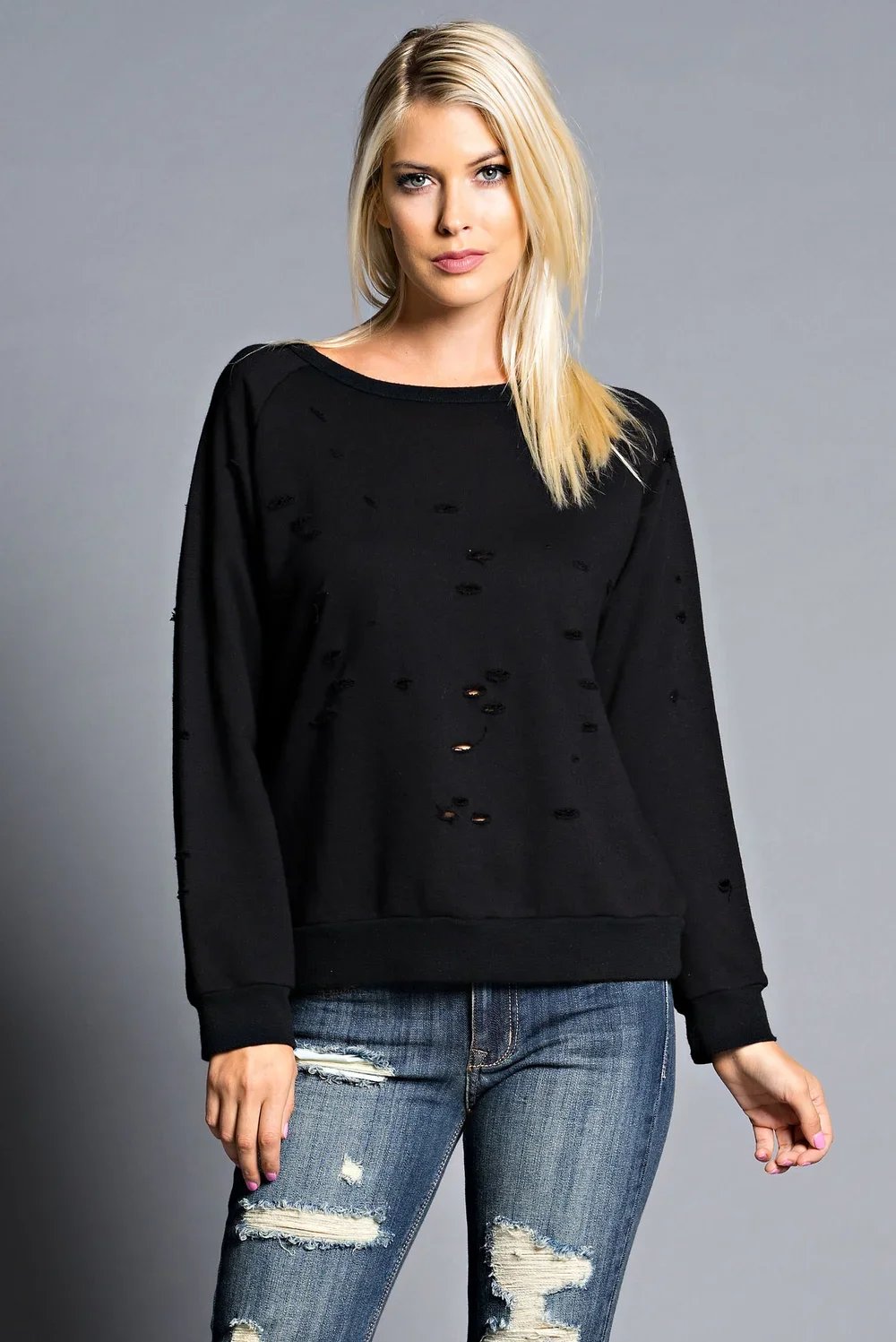 Woman wearing a black distressed sweatshirt and ripped jeans — Urban Nation women's collection